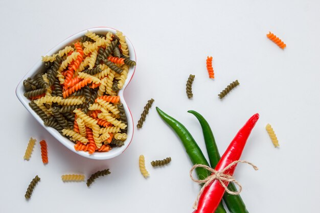 Pasta fusilli con pimientos picantes en un recipiente en la mesa blanca, vista superior.