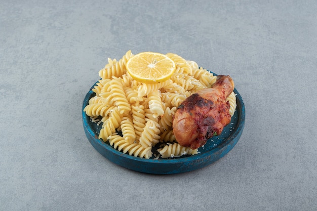 Pasta fusilli con pollo frito en placa azul.