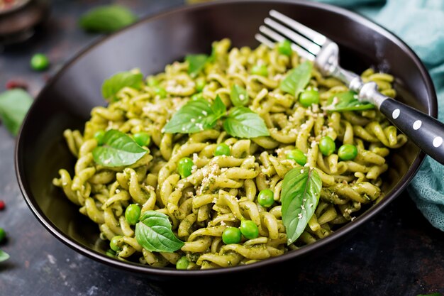 Pasta fusilli con salsa de pesto, guisantes y albahaca. Comida italiana.