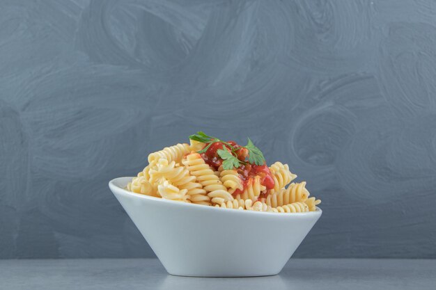 Pasta fusilli con salsa de tomate en un tazón blanco.