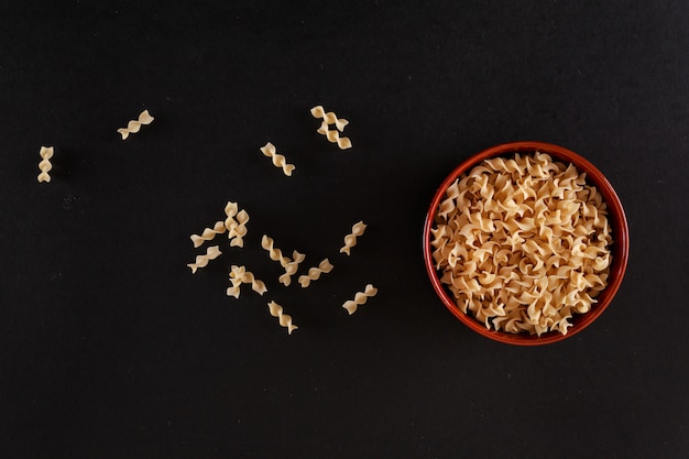 Foto gratuita pasta fusilli en el tazón de cerámica en la vista superior de la superficie negra