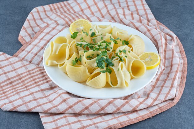 Pasta hervida con rodajas de limón en un plato blanco.