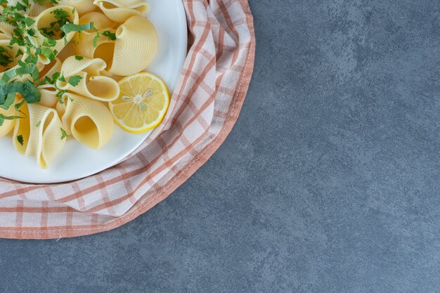 Pasta hervida con rodajas de limón en un plato blanco.