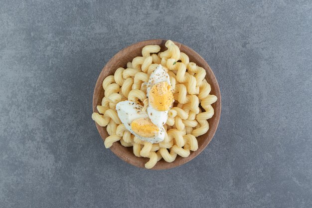 Pasta con huevos duros en un tazón de madera.