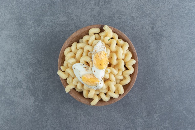 Pasta con huevos duros en un tazón de madera.