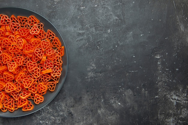 Pasta italiana en forma de corazón de la mitad superior vista en placa negra