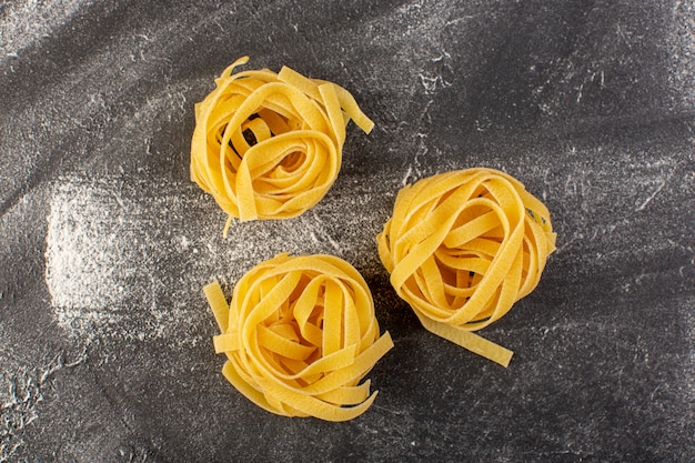 Pasta italiana en forma de vista frontal en forma de flor cruda y amarilla sobre gris