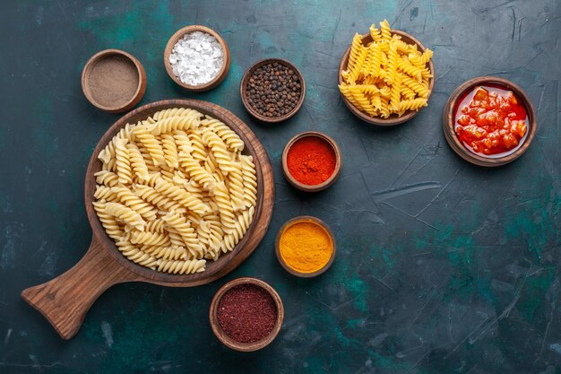 Pasta italiana en forma de vista superior con condimentos en el escritorio azul oscuro