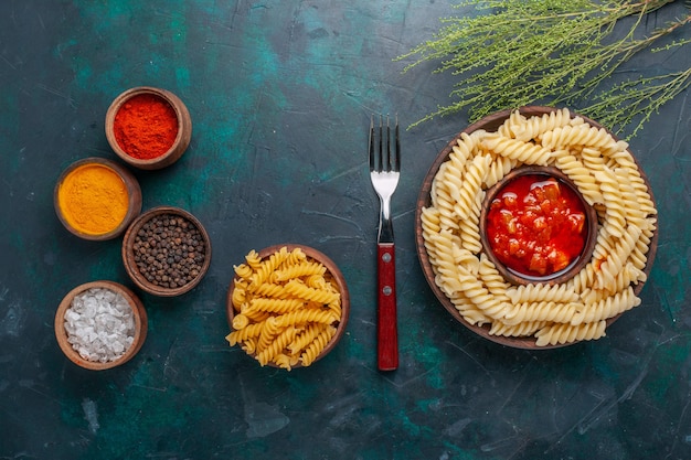 Pasta italiana en forma de vista superior con condimentos sobre el fondo azul oscuro