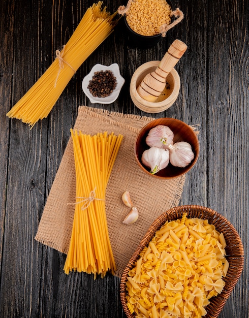 Foto gratuita pasta italiana stelline espagueti mortero linguini ajo mezclado penne farfalle rotini vista superior