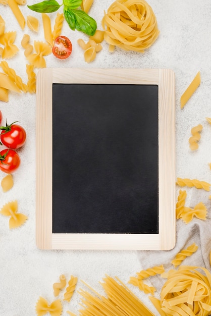 Foto gratuita pasta italiana y tomates al lado de pizarra