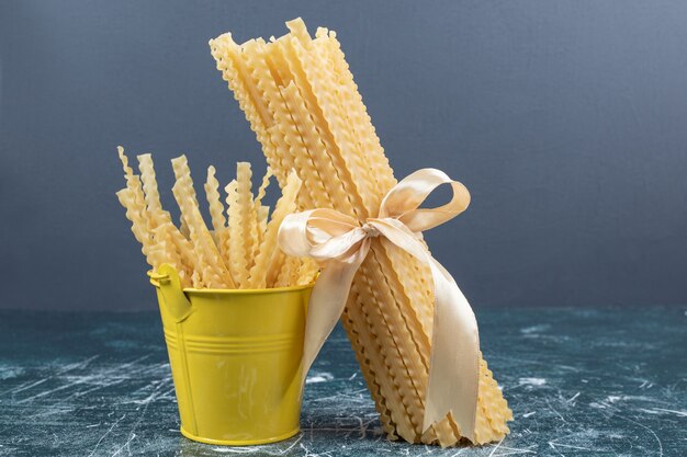 Foto gratuita pasta mafaldine cruda en balde y atada con cinta. foto de alta calidad