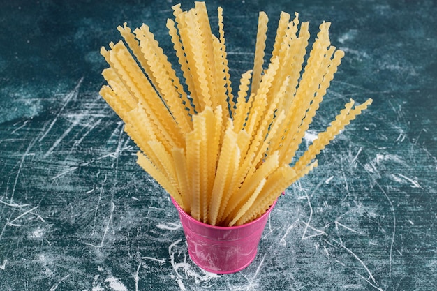 Foto gratuita pasta mafaldine cruda en cubo rosa.