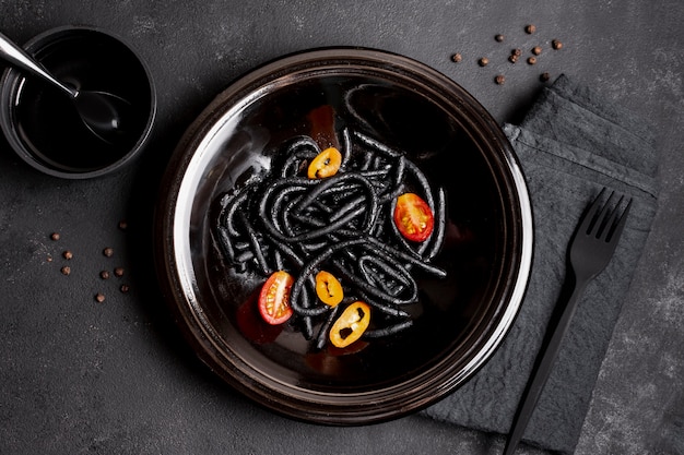 Pasta negra de camarones en plato con tenedor y salsa de soja