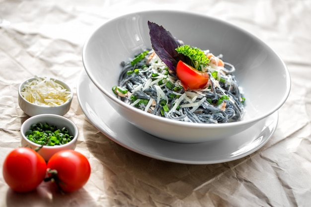 Pasta negra en salsa con cebolla verde y tomate