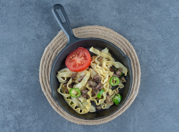 Foto gratuita pasta con partes de ternera en sartén negra.