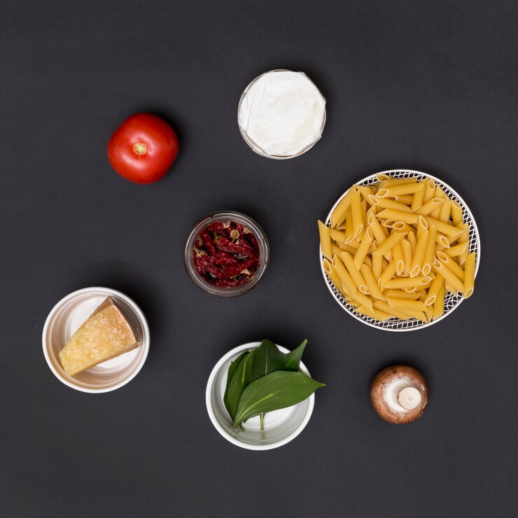 Foto gratuito pasta penne sin cocer e ingredientes dispuestos en el mostrador de la cocina