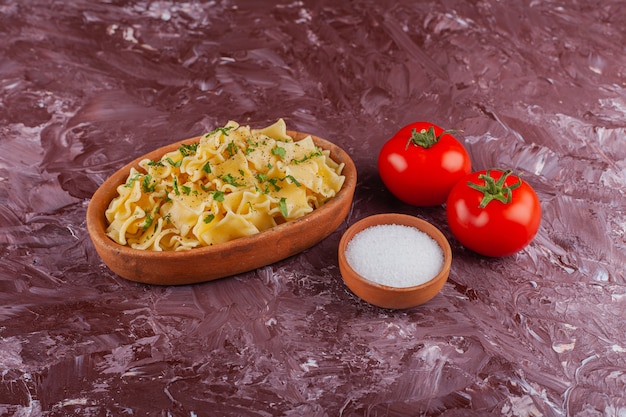 Pasta penne con mayonesa y tomates rojos frescos sobre una mesa de luz.