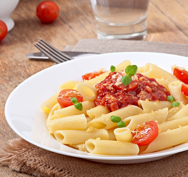 Pasta penne con salsa boloñesa, queso parmesano y albahaca