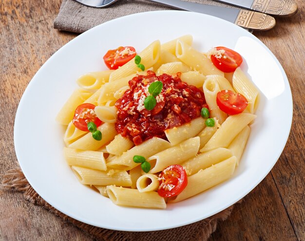 Pasta penne con salsa boloñesa, queso parmesano y albahaca