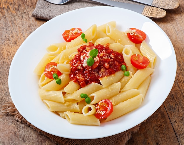 Pasta penne con salsa boloñesa, queso parmesano y albahaca