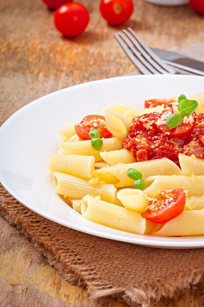 Pasta penne con salsa boloñesa, queso parmesano y albahaca