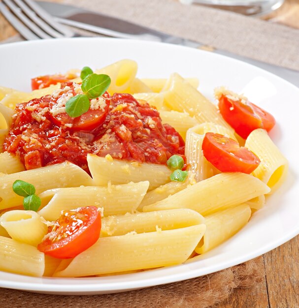 Pasta penne con salsa boloñesa, queso parmesano y albahaca