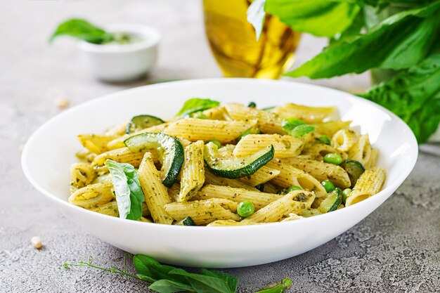 Pasta penne con salsa de pesto, calabacín, guisantes y albahaca. Comida italiana.