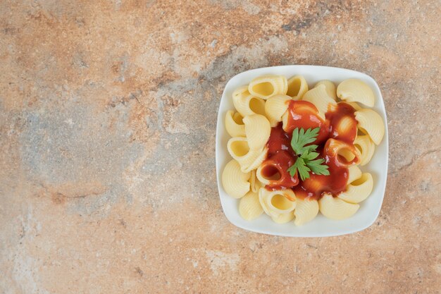 Pasta con perejil y salsa de tomate en tazón de fuente blanco