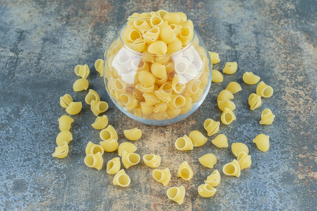 Pasta de pipa italiana en el recipiente, sobre la superficie de mármol.