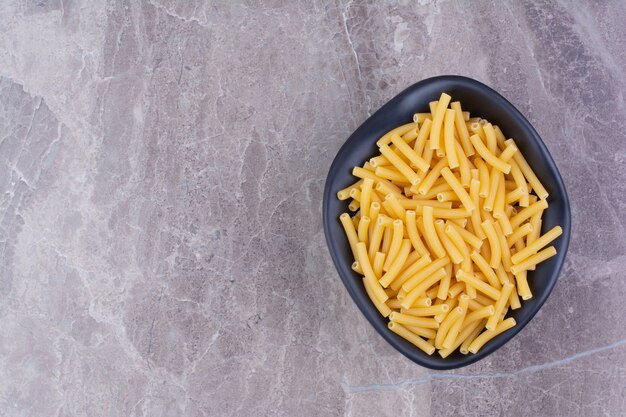 Pasta en un plato de cerámica negra sobre el mármol