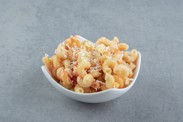 Pasta con queso rallado en tazón de fuente blanco.