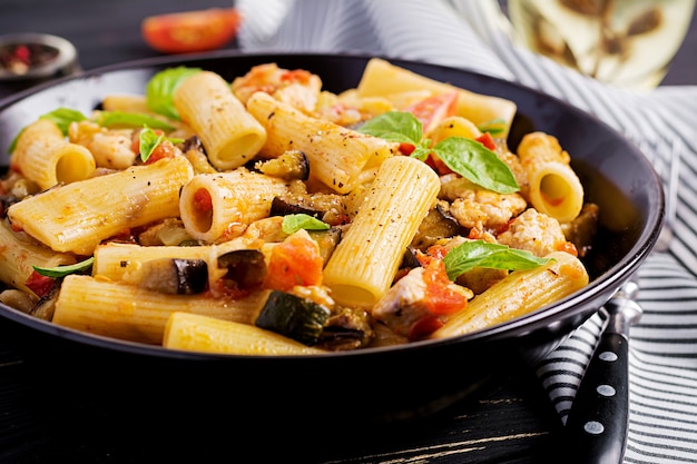 Pasta rigatoni con carne de pollo y berenjenas en salsa de tomate en un tazón