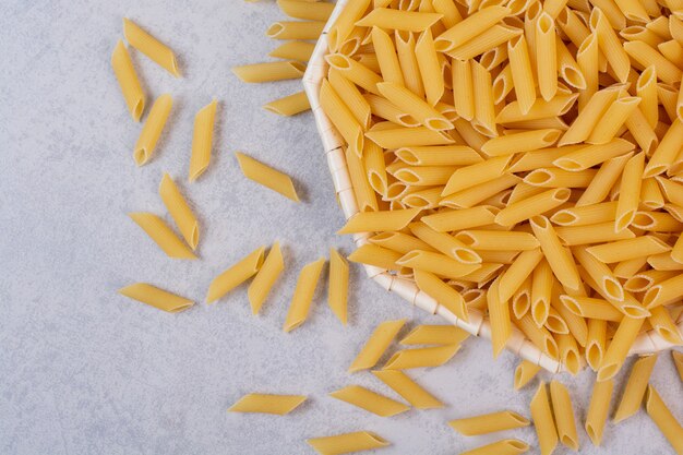 Pasta rigatoni cruda en tazón de fuente blanco