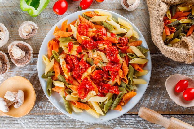 Pasta con salsa, tomate, champiñones, rodillo, pimienta en un plato