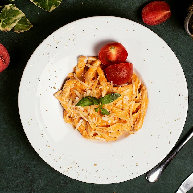 Pasta en salsa de tomate con parmesano picado, tomate y albahaca.