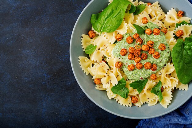 Pasta vegana Farfalle con salsa de espinacas y garbanzos fritos.