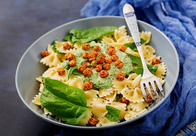 Pasta vegana Farfalle con salsa de espinacas y garbanzos fritos.