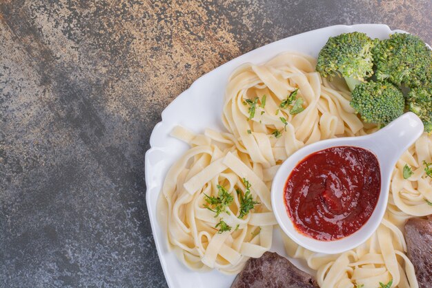 Pasta con verduras y pasta de tomate, carne en plato blanco