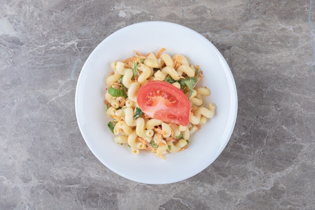 Pasta con verduras picadas en un plato blanco.