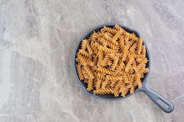 Pastas caseras en forma de espiral en una sartén negra.