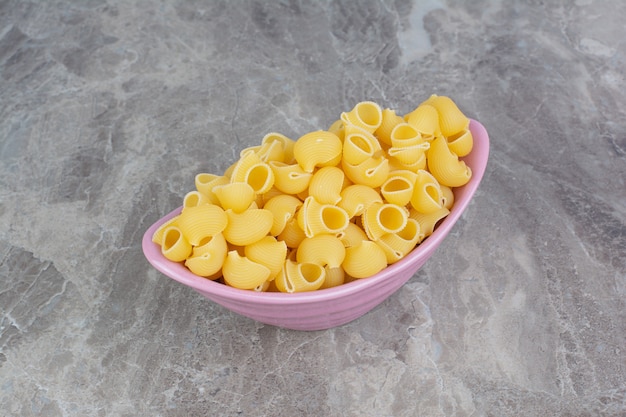 Foto gratuita pastas crudas en una bandeja metálica rosa sobre el mármol