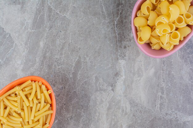 Pastas crudas en una bandeja metálica rosa sobre el mármol