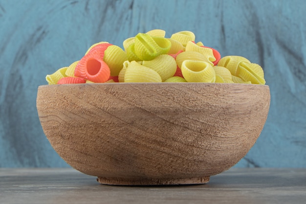 Foto gratuita pastas crudas de conchiglie en cuenco de madera.