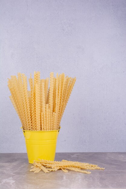 Pastas crudas en un cubo contenedor metálico amarillo