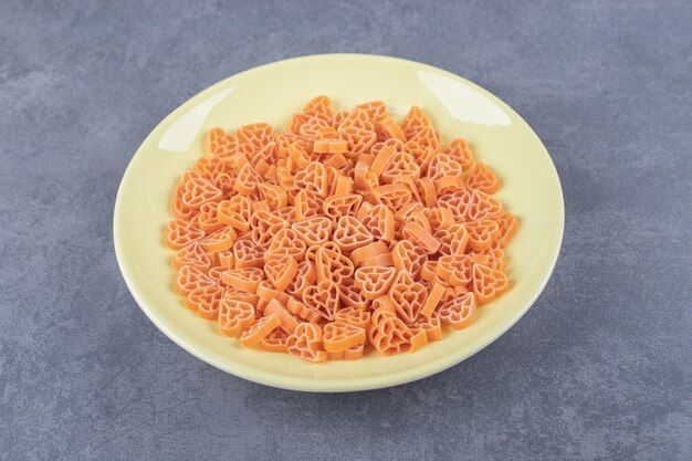 Pastas crudas en forma de corazón en placa amarilla.