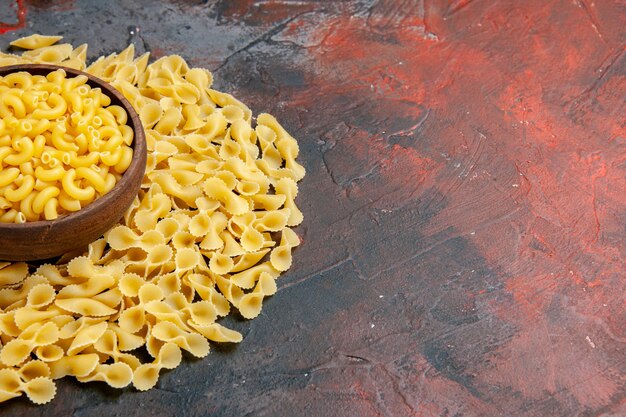 Pastas crudas de mariposa en un recipiente marrón sobre tabla de colores mezclados