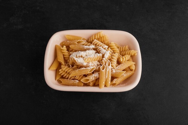 Pastas crudas con salsa de crema en platillo blanco.