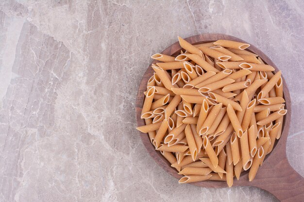 Pastas crudas en tazas de madera rústicas en espacio gris.