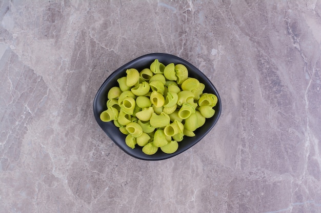 Foto gratuita pastas crudas verdes en un cuenco de cerámica sobre el mármol